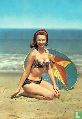 Vrouw met haarband en paarse bikini met motief en parasol op strand   - Afbeelding 1