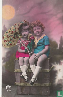 Jongen en meisje onder parasol met bloemen op kist - Image 1