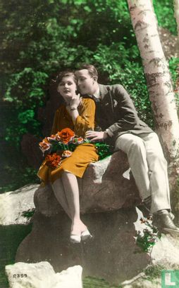 Jong stel zittend op rots bij boom - vrouw heeft rozen op schoot - Image 1