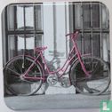 Lila fiets tegen muur/hekwerk - Image 1