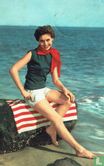 Vrouw zittend op roodgestreepte handdoek op rots aan strand - Bild 1