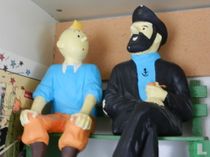 Tintin and Captain Haddock on bench with Bobby to their feet.