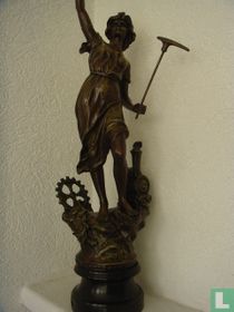 Metalen beeld op sokkel met pikhouweel
