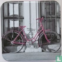 Lila fiets tegen muur/hekwerk
