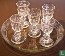 Set of miniature wine glasses on glass saucer